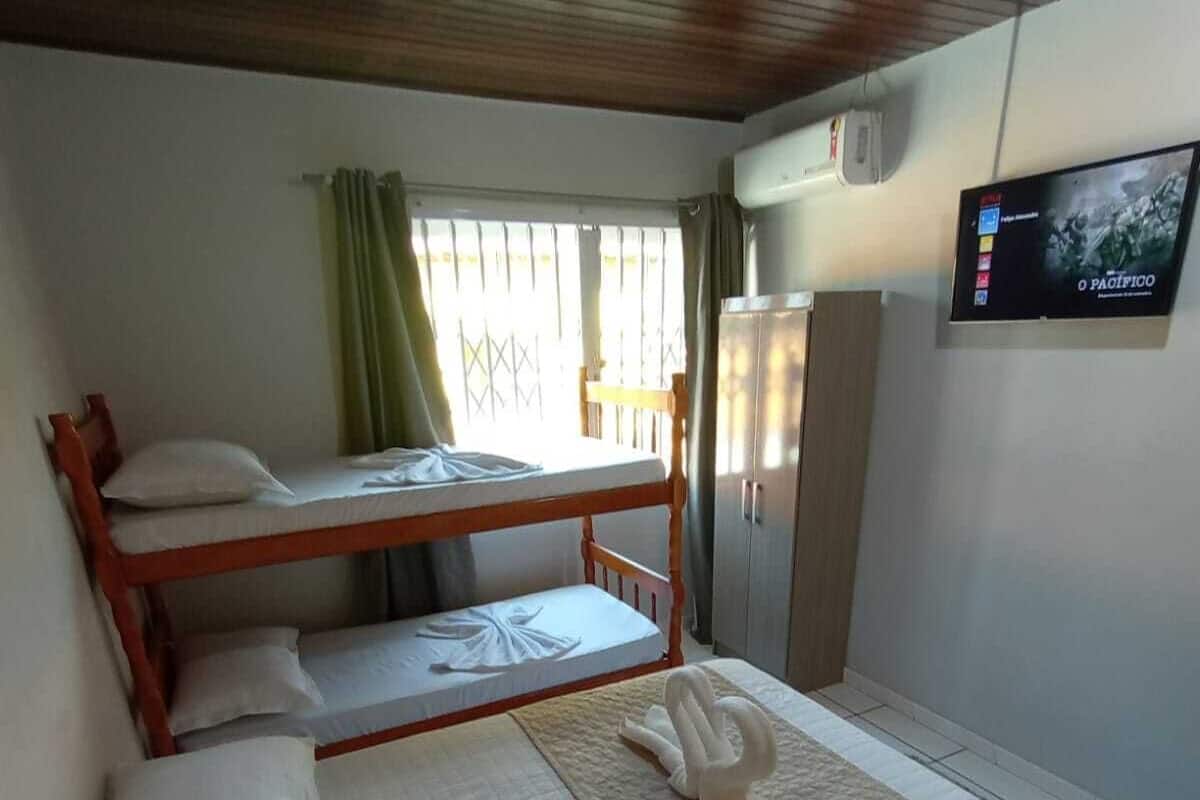A room with bunk beds, a flat-screen TV, and a window with curtains.