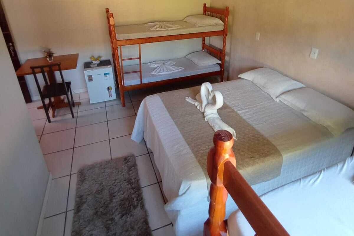 A room with a bunk bed, a small desk with a chair, and a rug on the floor.