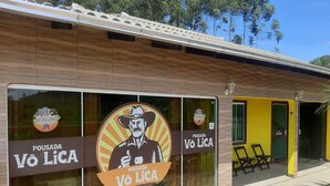 A building with large windows displaying a logo and the name "Pousada Vô Lica". - Pousada Vô Lica  (Penha)