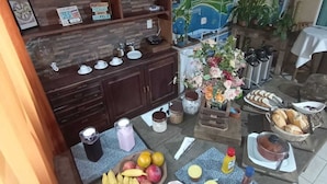 A kitchen area with wooden cabinets, a map on the wall, and a dining table set with food and drinks. - Pousada Vô Lica  (Penha)