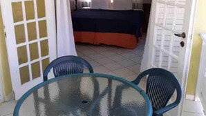 A room with a bed, a table with chairs, and a door leading to another room. - Endless Summer Brookside (Ocho Rios)