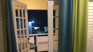 An open door leading to a balcony with a chair, a tiled floor, and a view of a building at night. - Endless Summer Brookside (Ocho Rios)