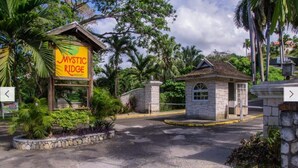 Een bord van Mystic Ridge Resort met een klein stenen gebouw op de voorgrond.