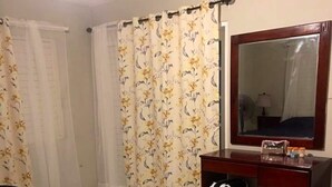 Een hotelkamer met een bed, een dressoir, een spiegel en een radiator.