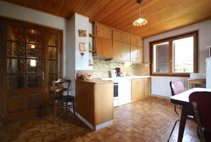 Una cocina con armarios de madera, una isla central, una mesa de comedor con sillas y un amplio ventanal que proporciona luz natural.