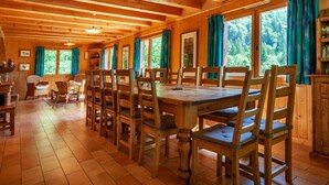 A wooden cabin with a large dining table and chairs, surrounded by windows with curtains. - Chalet, 3rd floor, balcony, fireplace or stove, tv, 215m², Morzine (Montriond)