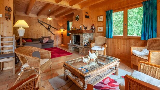 A cozy wooden cabin interior with a fireplace, wicker furniture, and a view of the outdoors. - Chalet, 3rd floor, balcony, fireplace or stove, tv, 215m², Morzine (Montriond)