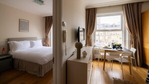 Een hotelkamer met een bed, bureau, stoel en raam met gordijnen.