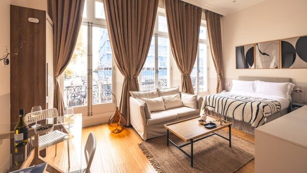 A modern bedroom with a sofa, a bed, a coffee table, and a dining area with a table and chairs. - The Courtfield - Deluxe Studio in Kensington (London)