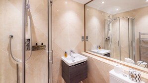 A modern bathroom with a glass-enclosed shower, a vanity with a sink, and a large mirror.