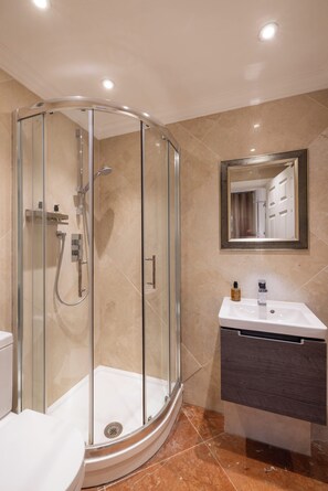 Une salle de bain moderne avec une douche à parois de verre, un lavabo blanc et un miroir doté d’un cadre décoratif.