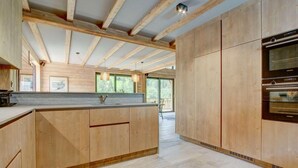 Una cocina moderna con armarios de madera, horno empotrado y un amplio ventanal que proporciona luz natural.