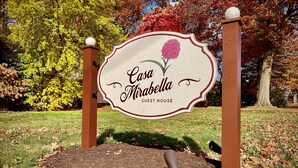 Señal para Casa Mirabella Guest House con un diseño decorativo e ilustración floral.