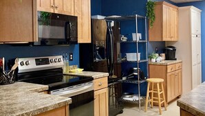 Una cocina con armarios de madera, microondas, estufa y refrigerador.