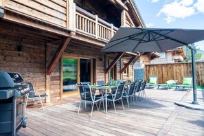 A wooden cabin with a deck, outdoor seating, and a grill. - Chalet, swimming pool, sauna, terrace, fireplace or stove, parking, tv, ski locker, 175m², Morzine (Morzine)