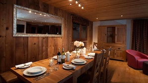 A wooden dining room with a long table set for a meal, a mirror on the wall, and a red chair in the corner. - Chalet, 70m from ski lifts, view mountain, swimming pool, sauna, fireplace or stove, parking, tv (Morzine)