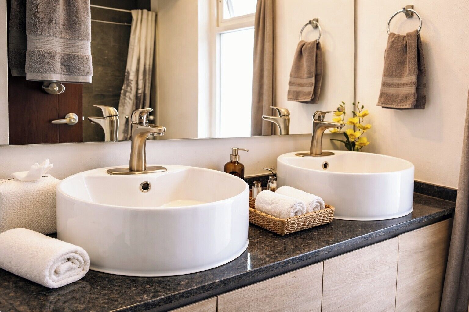 Une salle de bain avec deux lavabos blancs, un miroir et des serviettes.