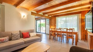 A cozy living room with a sofa, a coffee table, and a dining area with wooden chairs and a table. - 100m from ski slopes, Ground floor, terrace, parking, tv, ski locker, 67m², Morzine (Morzine)