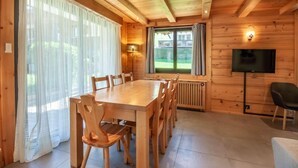 A wooden-paneled room with a large dining table, chairs, a TV, and a window with curtains. - 100m from ski slopes, Ground floor, terrace, parking, tv, ski locker, 67m², Morzine (Morzine)