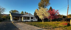 Ein eingeschossiges Haus mit Veranda, Garage und gepflegtem Rasen.
