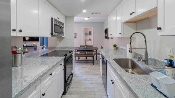 A modern kitchen with white cabinets, a stainless steel sink, and a built-in microwave.