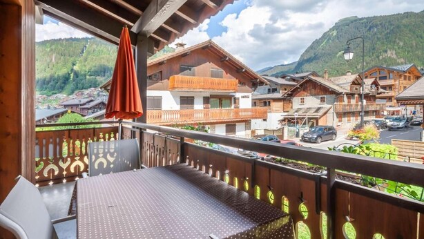 A balcony with a table and chairs, overlooking a mountain village with traditional wooden houses. - 100m from ski slopes, 1st floor, balcony, parking, tv, ski locker, 40m², Morzine (Morzine)