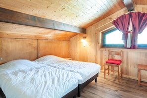 A wooden cabin room with a bed, a chair, and a window with curtains. - 100m from resort center, 1st floor, balcony, parking, tv, ski locker, 40m², Morzine (Morzine)