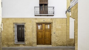 Ein Gebäude mit einer Holztür, einem Fenster mit Metallgitter und einem Balkon mit schmiedeeisernem Geländer.