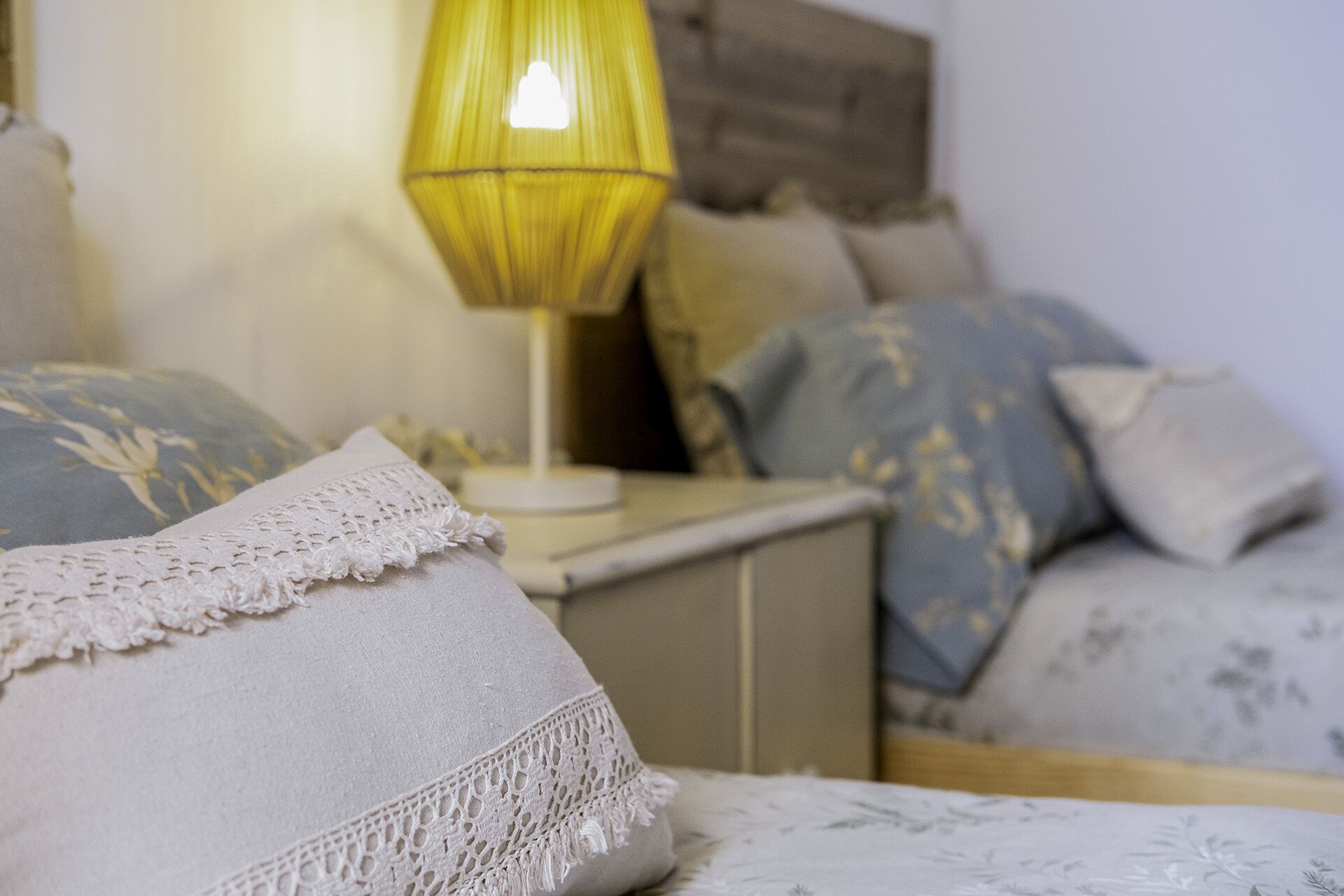Un lit avec un oreiller orné de dentelle, une lampe de chevet et une literie à motifs.
