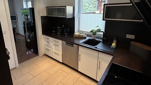Een moderne keuken met een ingebouwde oven, een magnetron en een spoelbak. Er is een raam dat natuurlijk licht en uitzicht op de omgeving biedt.