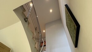 Een moderne trap met een metalen leuning, marmeren treden en een bordje aan de muur.