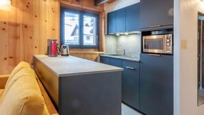 A compact kitchen with a central island, built-in appliances, and a window providing a view of the outside. - 100m from resort center, 1st floor, balcony, parking, tv, ski locker, 40m², Morzine (Morzine)