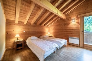 A cozy wooden cabin bedroom with two beds, a small nightstand, and a window with a view of the forest. - Chalet, 3rd floor, view mountain, sauna, balcony, fireplace or stove, tv, 120m², Morzine (Morzine)