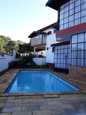 A two-story house with a swimming pool, a covered patio, and a staircase leading to the upper level.