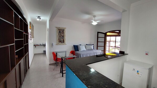 A compact kitchen with a dining area, a bed, and a small window.