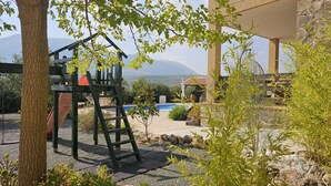 Un jardin avec une balançoire, une piscine et une vue sur les montagnes.