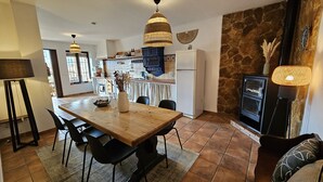 Une cuisine moderne avec une table à manger en bois, des chaises noires et une cheminée en pierre.