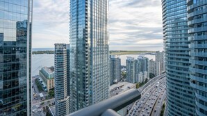 Un quartier urbain dense, avec de hauts immeubles aux façades vitrées modernes, une autoroute très fréquentée et une étendue d'eau en arrière-plan.