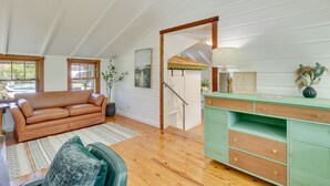 A spacious loft with a high ceiling, a wooden floor, a green desk with drawers, a leather sofa, and a staircase leading to an upper level. - Mount Dora Home: Private Pool & Tropical Bar! (Mt Dora)