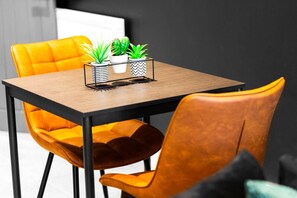 A dining area with a wooden table, two potted plants, and two yellow chairs.