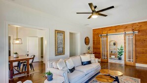 A spacious living room with a white sofa, wooden coffee table, and a ceiling fan. - Walk to Dtwn: 'Tyler Tudor' w/ Backyard (Tyler)
