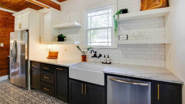 A kitchen with white subway tiles, a stainless steel refrigerator, black cabinets, and a window with a plant. - Walk to Dtwn: 'Tyler Tudor' w/ Backyard (Tyler)
