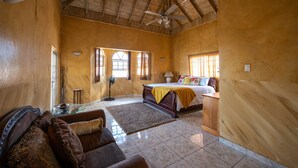 Een ruime kamer met een bed, een bank, een ventilator en een raam.