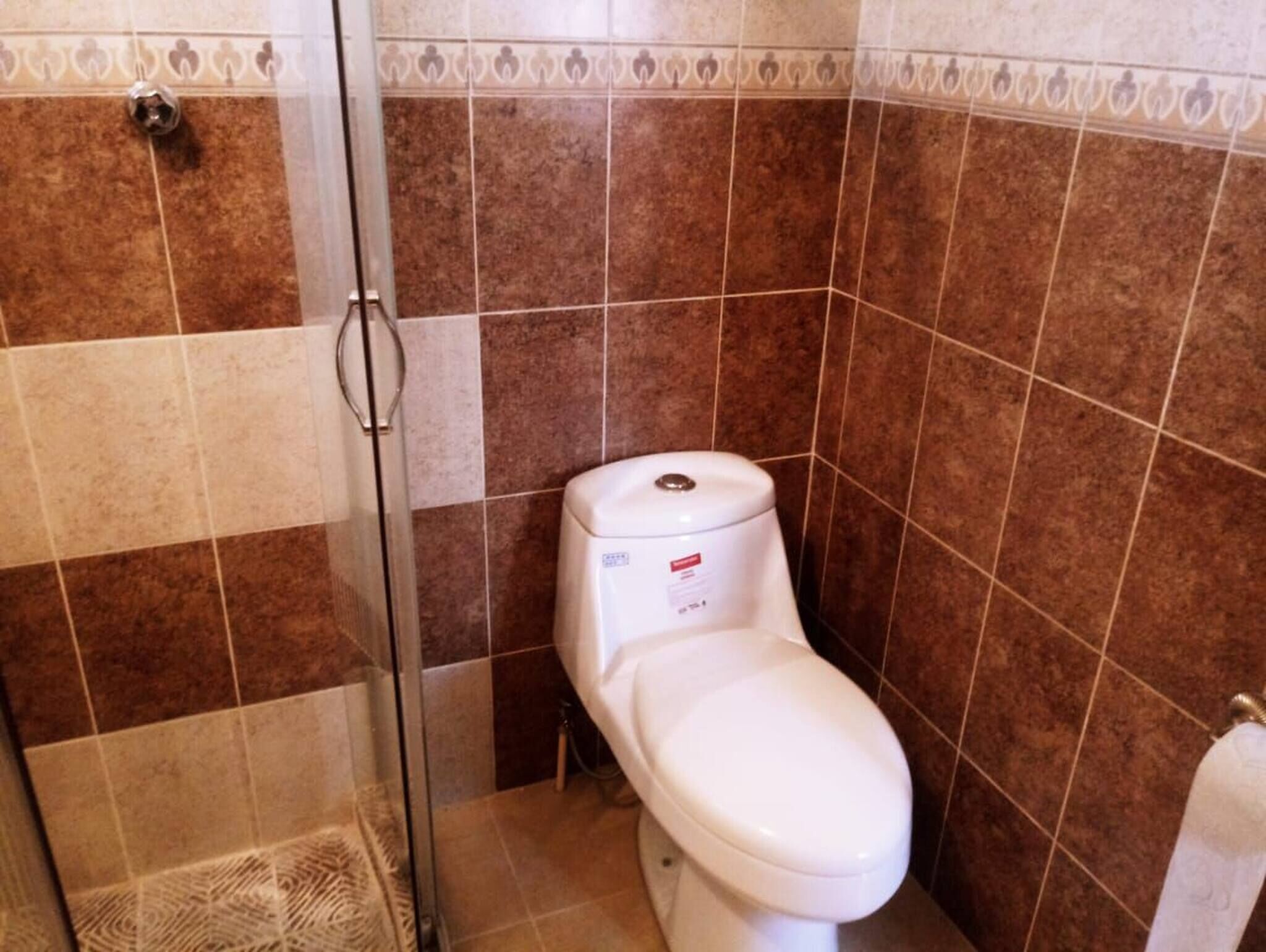 A bathroom with a toilet, shower, and tiled walls.