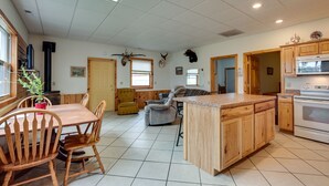 Una cocina amplia con armarios de madera, una isla central y un comedor con sillas de madera.