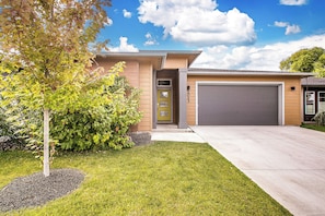 A modern two-story house with a garage, a well-maintained lawn, and mature trees. - Top Rated • Spotless • Prime Central Location • Where Guests Return (Meridian)
