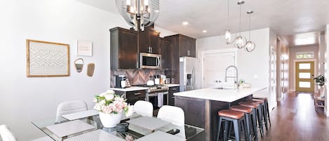 A modern kitchen with dark wood cabinets, stainless steel appliances, and a central island with stools.