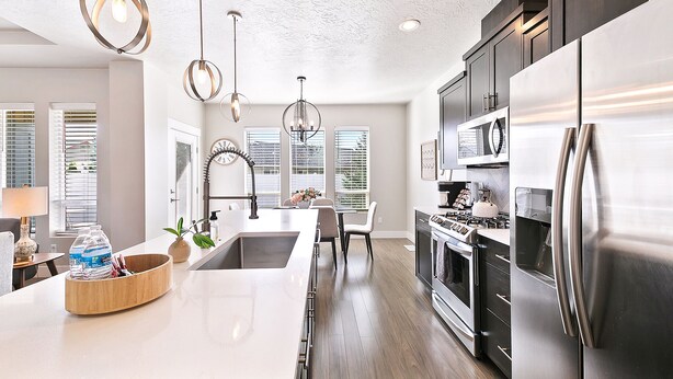 A modern kitchen with stainless steel appliances, a large island, and pendant lighting.