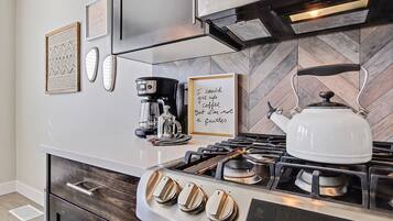 Una cocina moderna con estufa a gas, cafetera y hervidor.