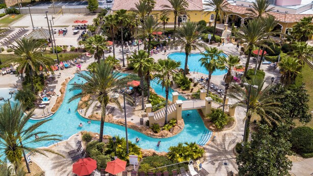 A resort with a large pool area, palm trees, and a building with a red-tiled roof. - Newly Renovated Townhouse! (Davenport)